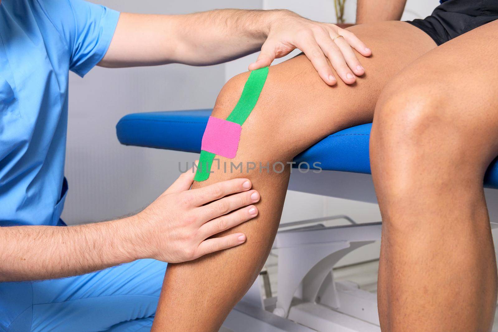 Physical therapist applying kinesio tape on male patient knee. Kinesiology, physical therapy, rehabilitation concept. close up. High quality photo