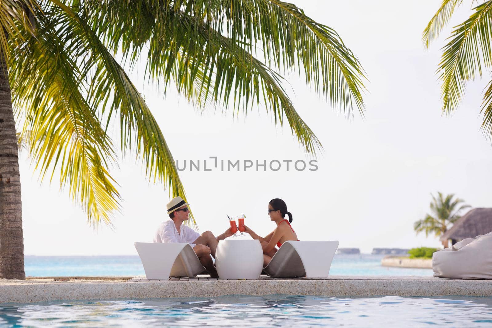 happy young couple relax and take fresh drink at summer vacation on swimmin pool