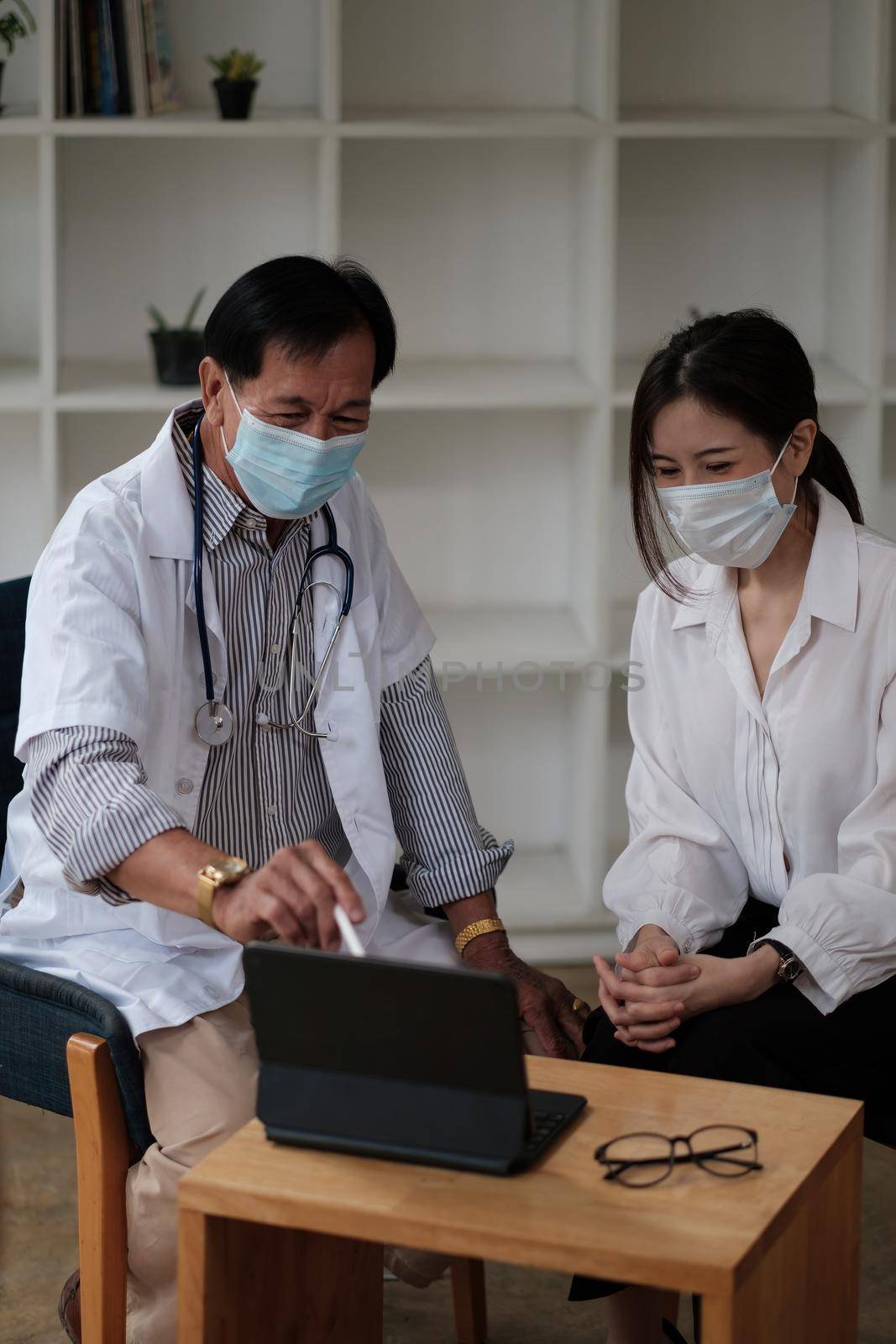 Senior doctor wearing safety protective mask supporting and cheering up young patient during home visit during virus and illness protection, home quarantine. COVID-2019. by nateemee