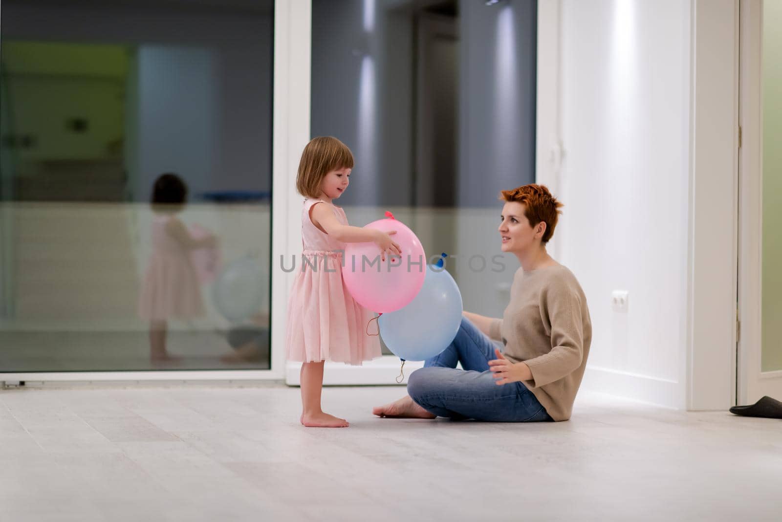 happy family spending time together young redhead mother and cute little daughter having fun while playing with balloons near the window on beautiful evening at home