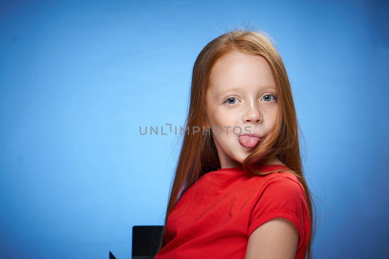 cheerful cute red-haired girl childhood blue background. High quality photo