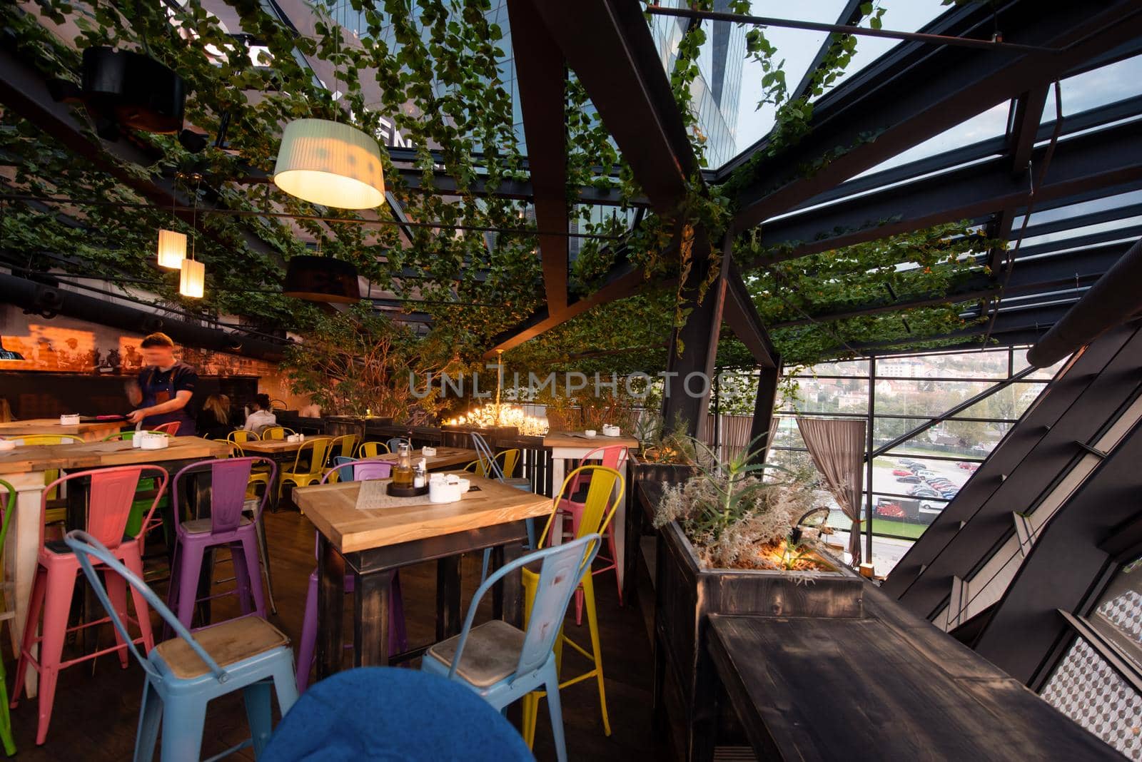 blurred people in modern cafe interior decorate with hanging plant and window glass around the space. restaurant background surrounded with nature