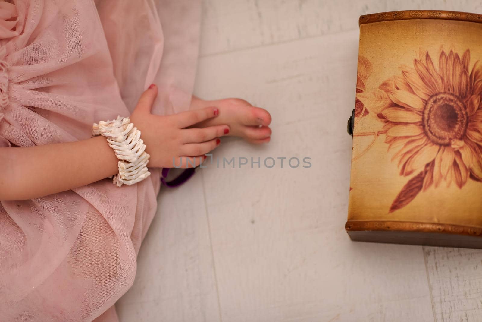 beautiful cute little girl in pink dress enjoying while playing with mother's jewelry from box on the floor at home