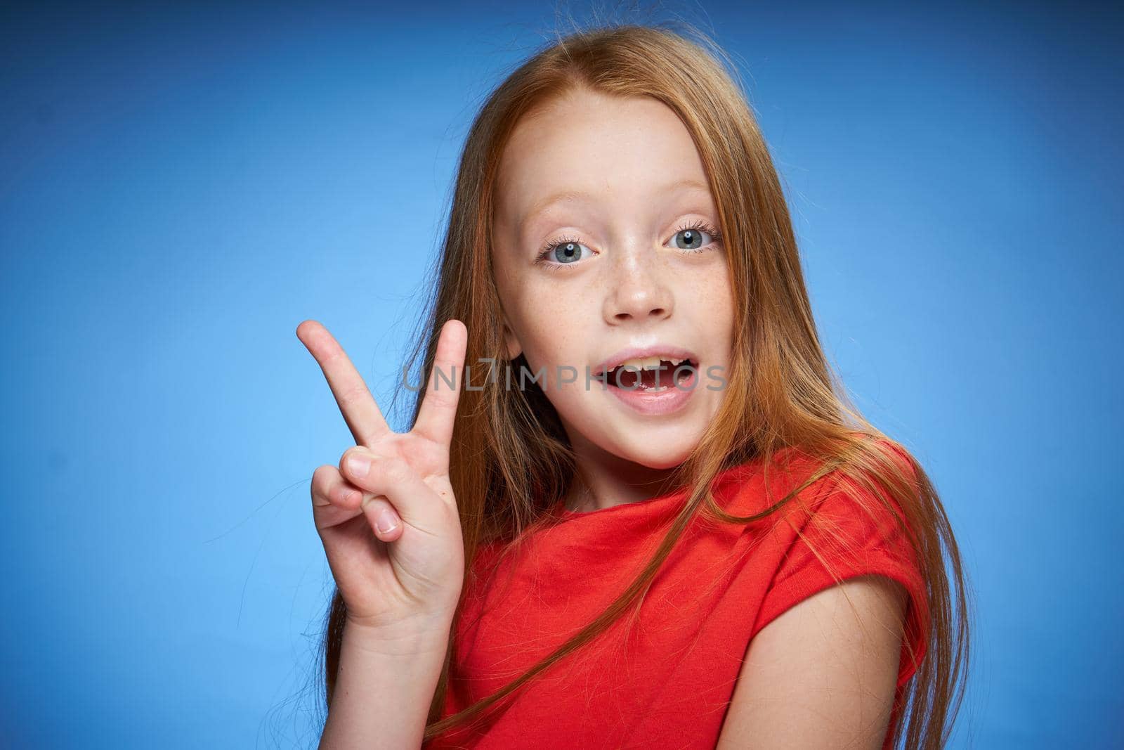cute red-haired girl in red t-shirt emotions blue background. High quality photo