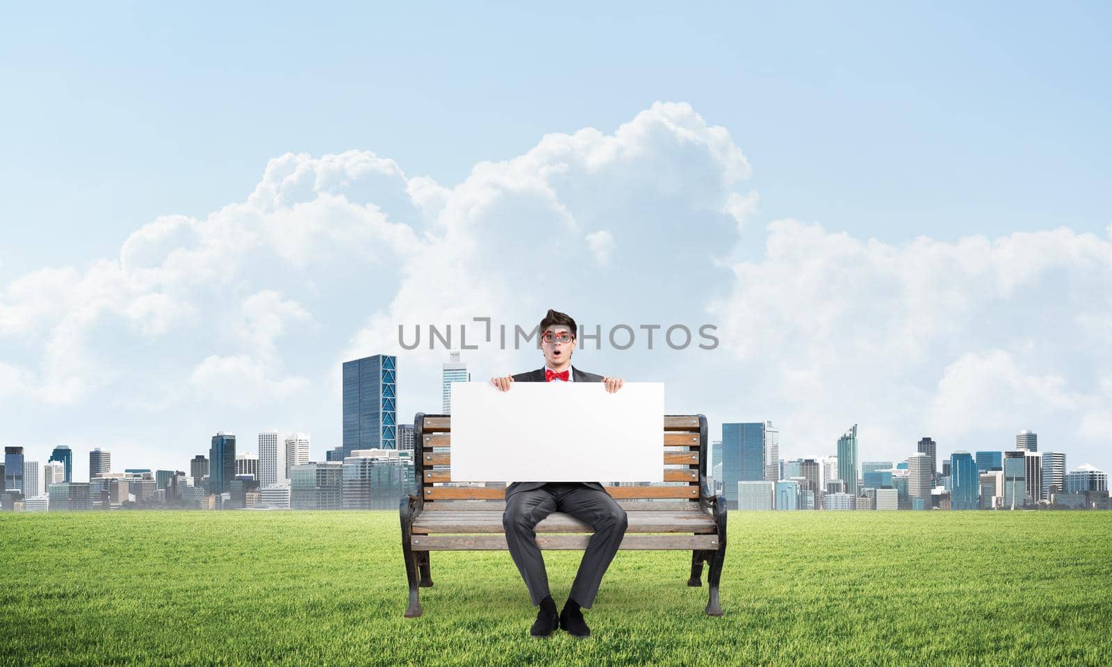 Young businessman sits on a wooden bench and holds a large white banner