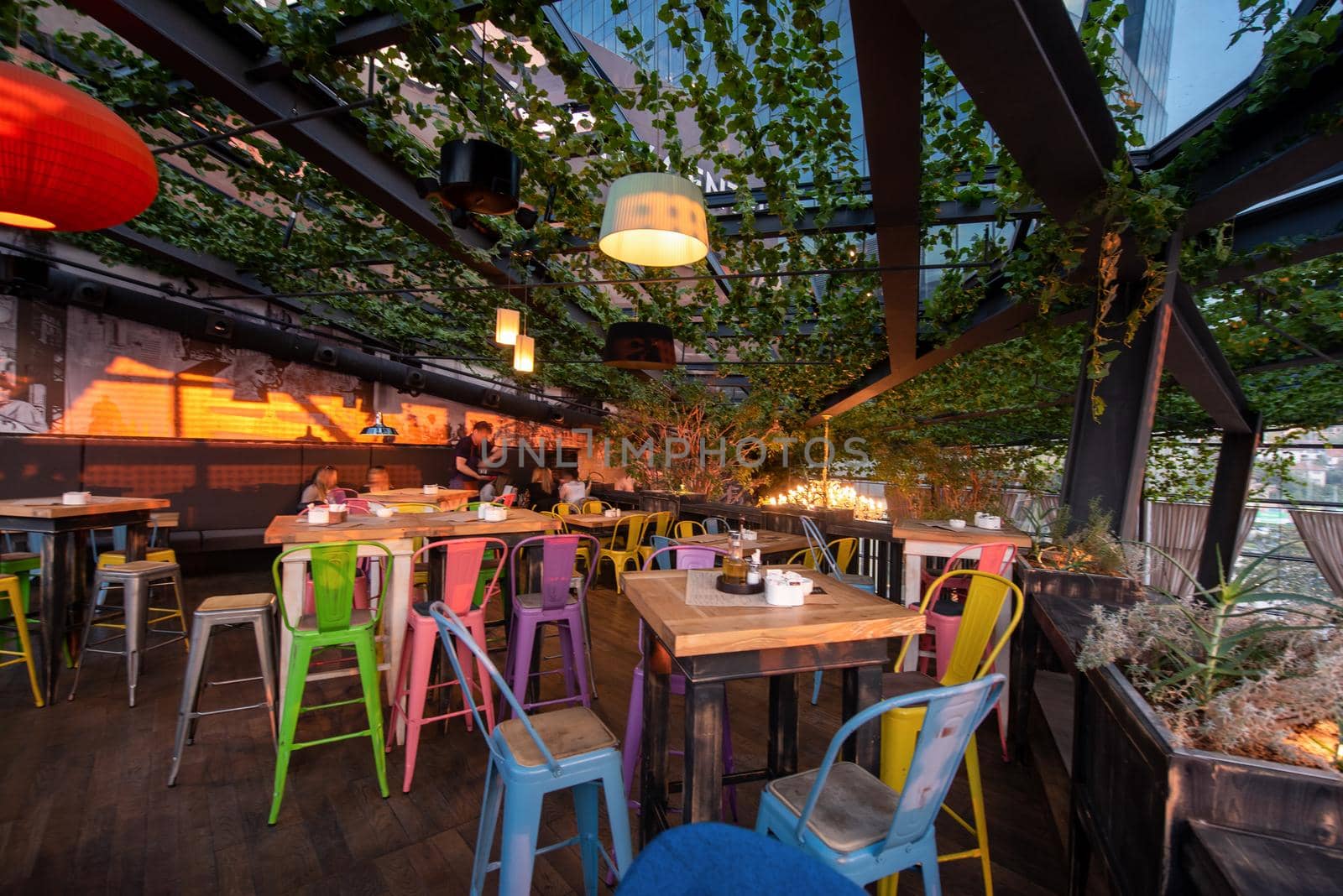 blurred people in modern cafe interior decorate with hanging plant and window glass around the space. restaurant background surrounded with nature