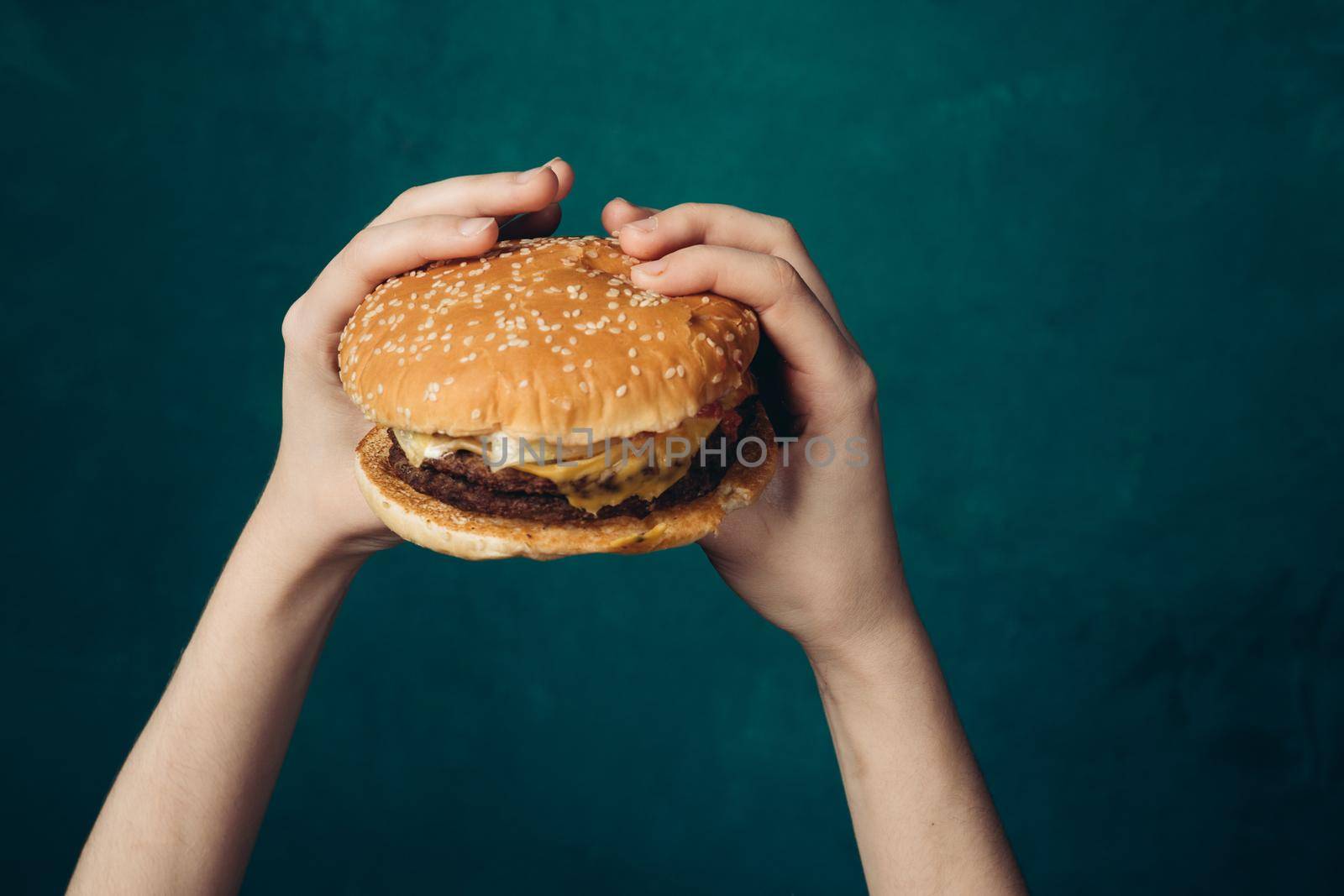 hamburger in hands close-up fast food green background. High quality photo