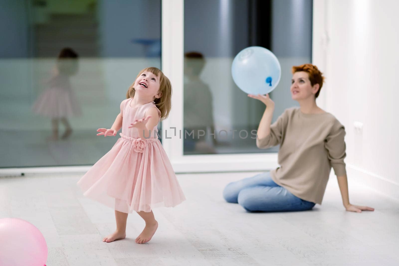 mother and cute little daughter playing with balloons by dotshock