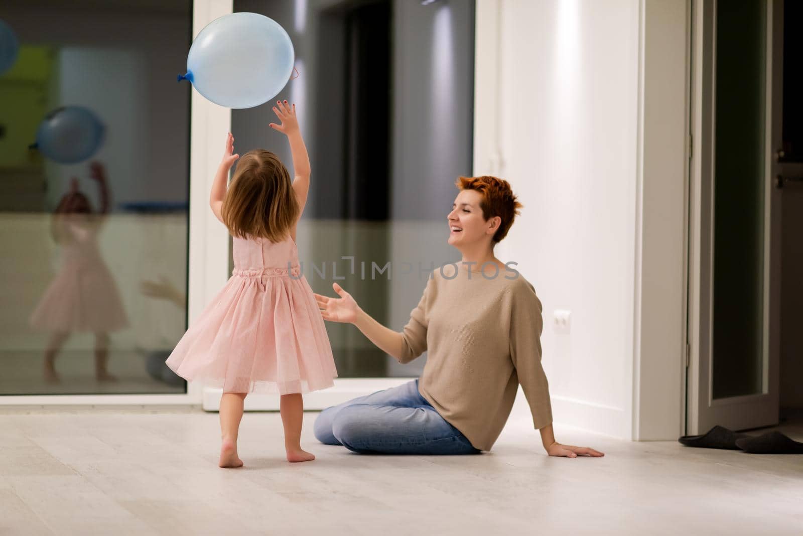 happy family spending time together young redhead mother and cute little daughter having fun while playing with balloons near the window on beautiful evening at home