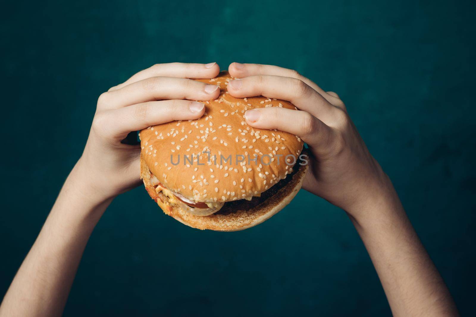 hamburger in hands close-up fast food green background by Vichizh