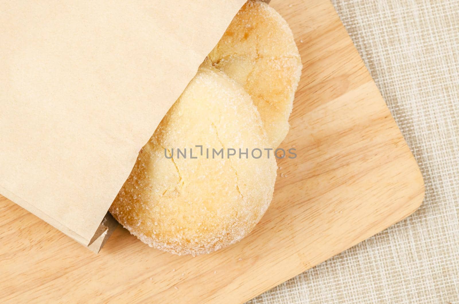 Homemade bread with cream and sugar on top in paper bag.