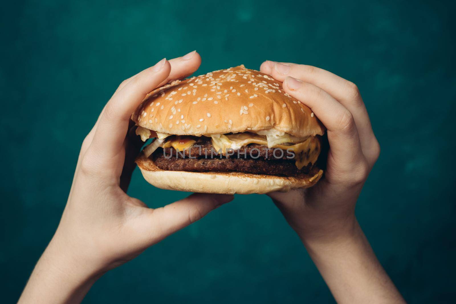 hamburger in hands close-up fast food green background by Vichizh