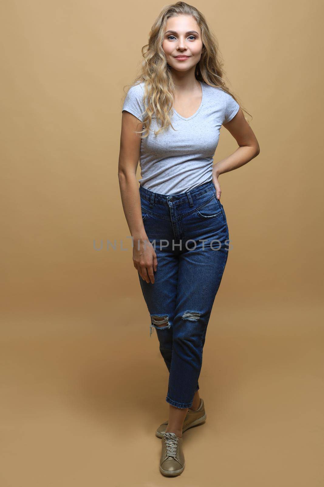 Full length photo of charming young woman in casual wear over beige background