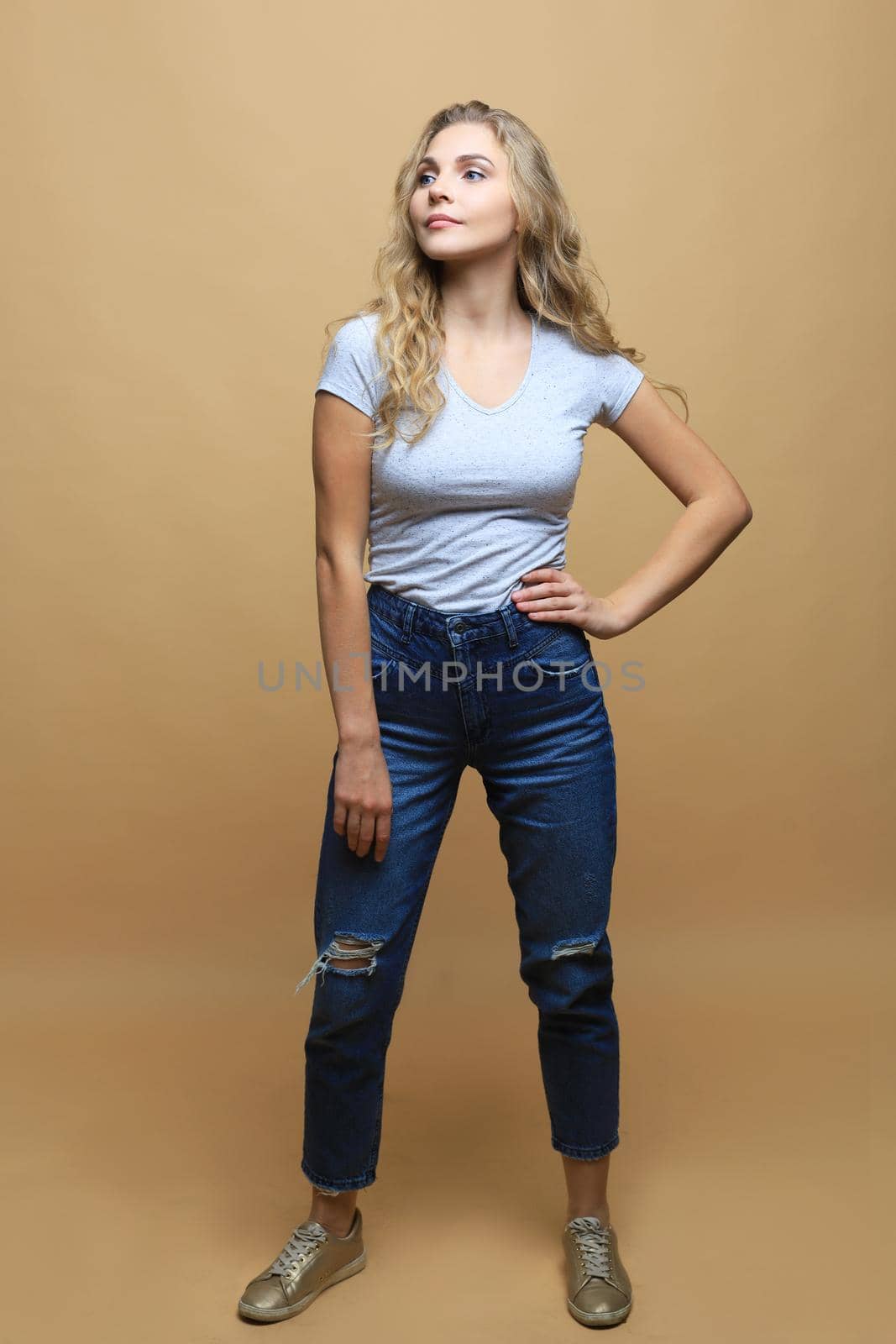 Full length photo of charming young woman in casual wear over beige background