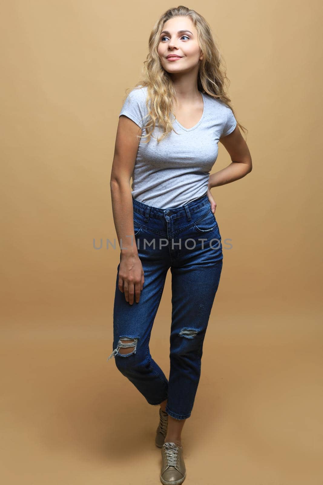 Full length photo of charming young woman in casual wear over beige background. by tsyhun