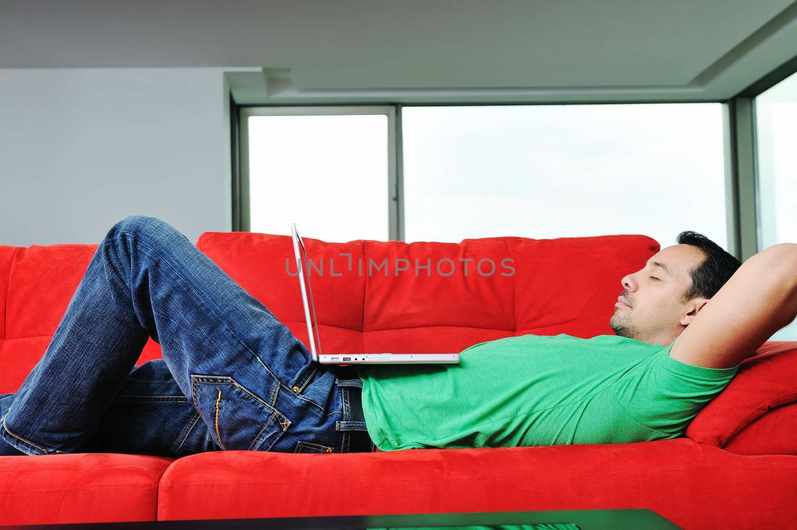 man relaxing on sofa and work on laptop computer by dotshock