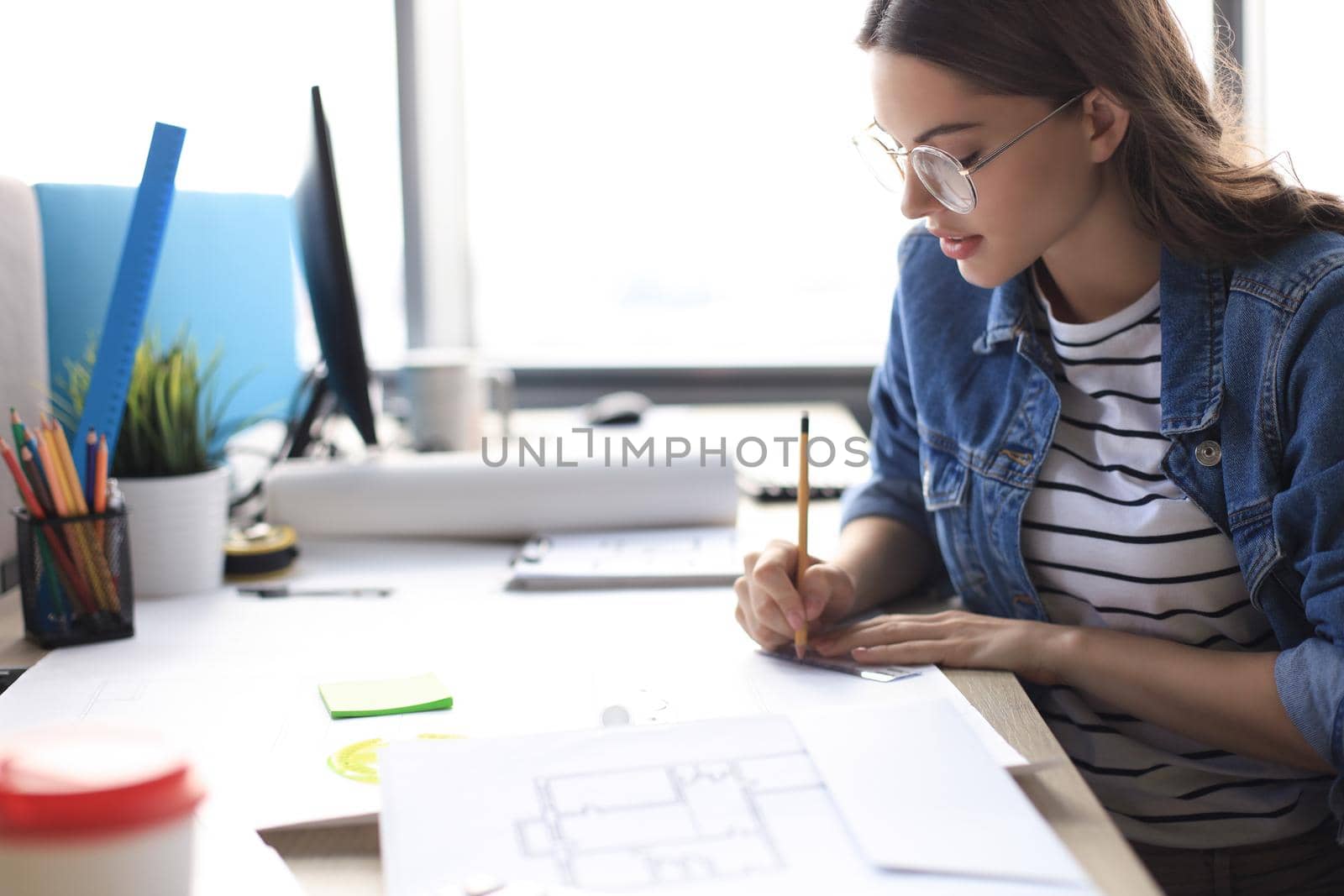 Concentrated young woman writing something down while working in the office