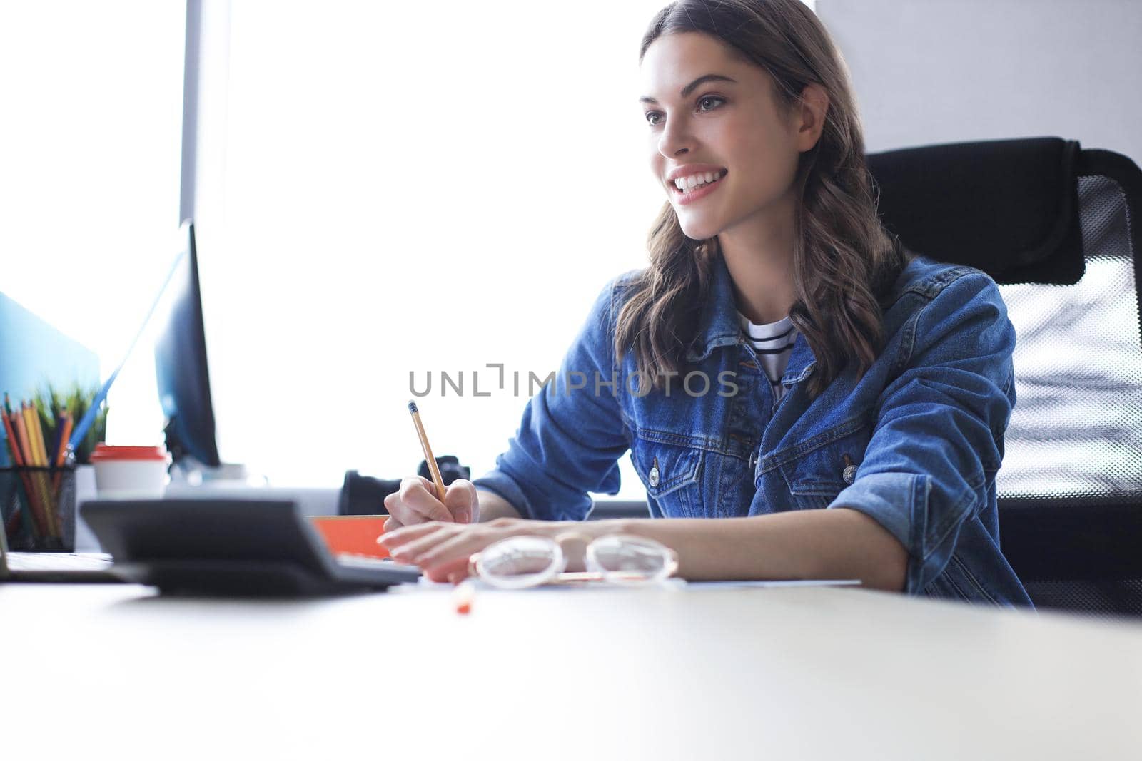 Concentrated young woman writing something down while working in the office. by tsyhun