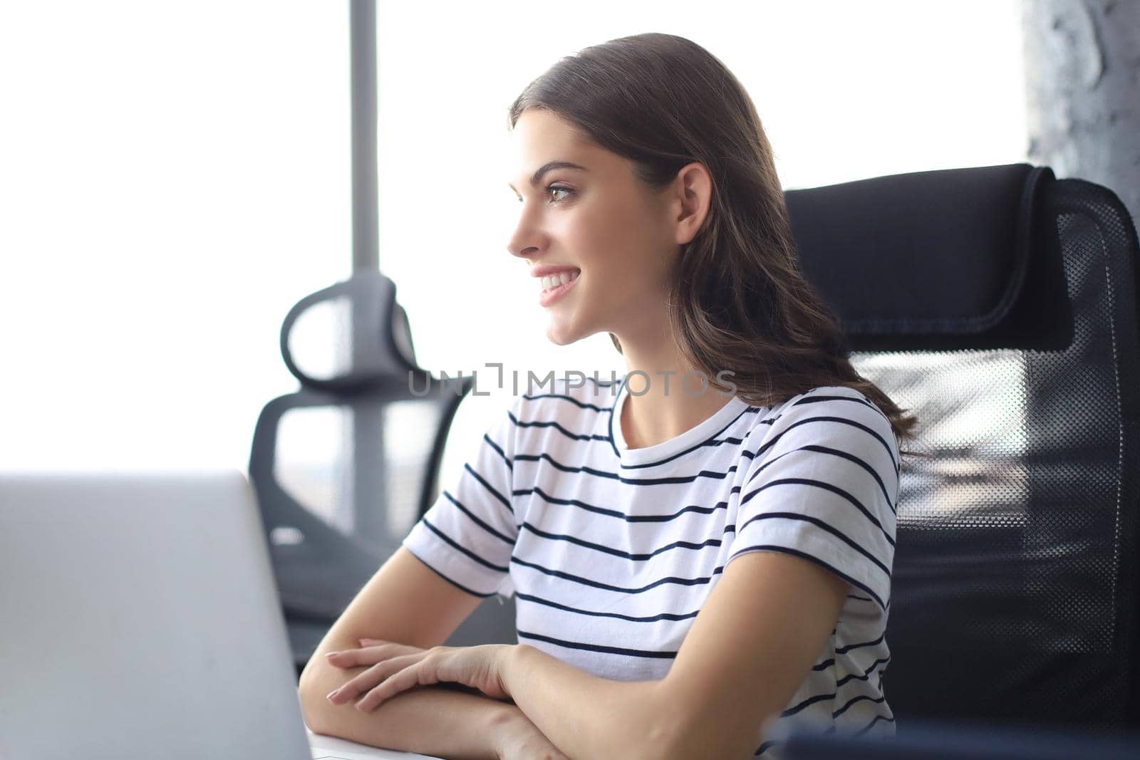 Beautiful business woman in smart casual wear working on laptop in the office.