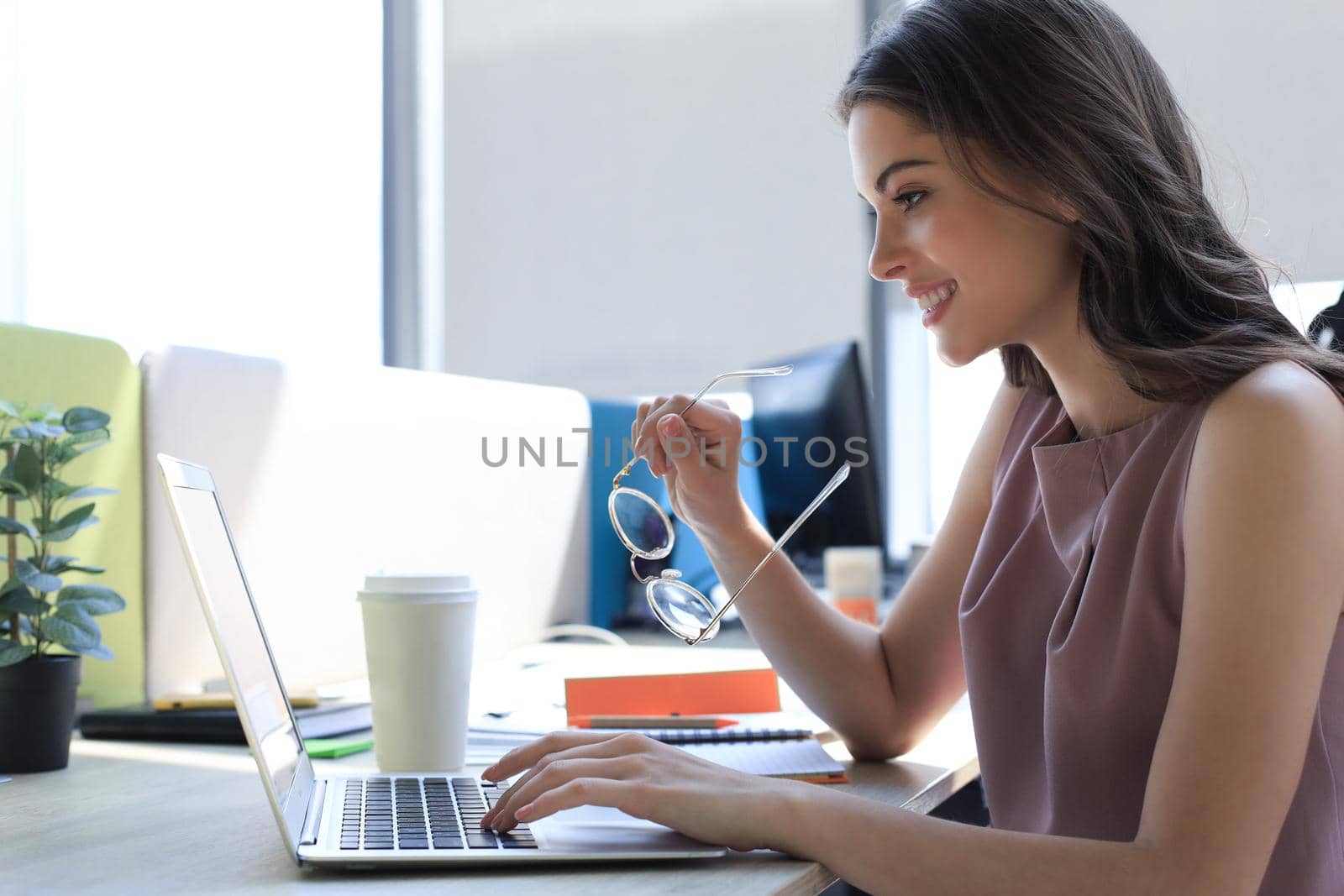 Beautiful business woman in smart casual wear working on laptop in the office.
