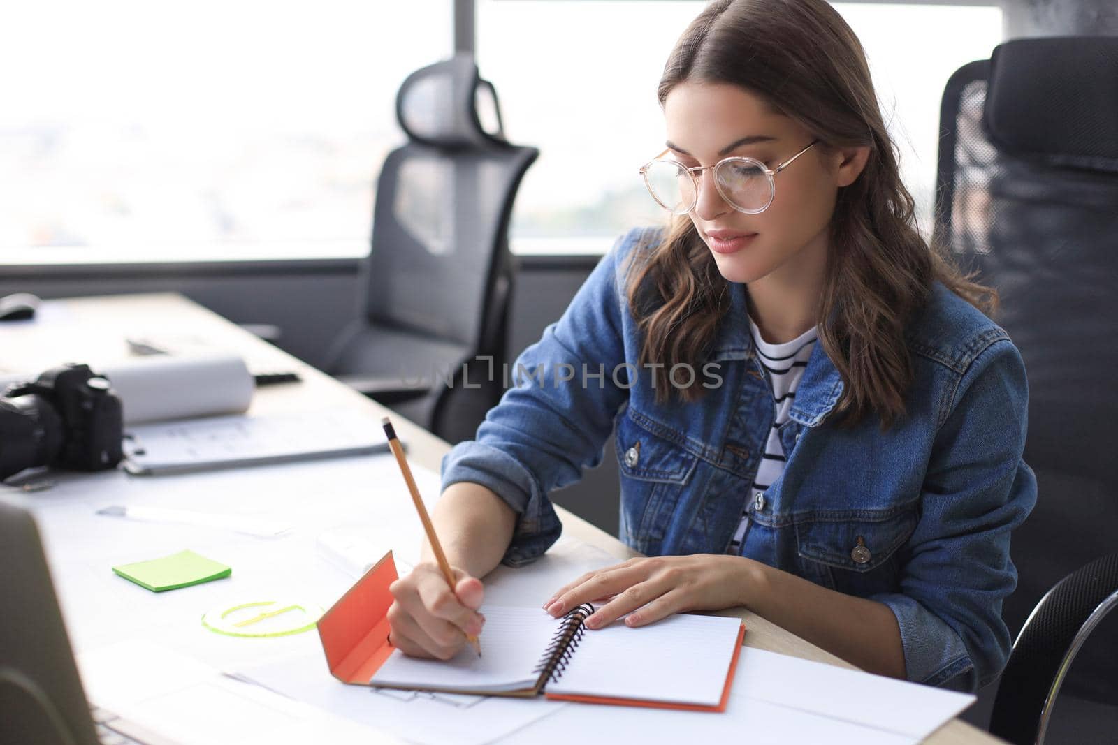Concentrated young woman writing something down while working in the office