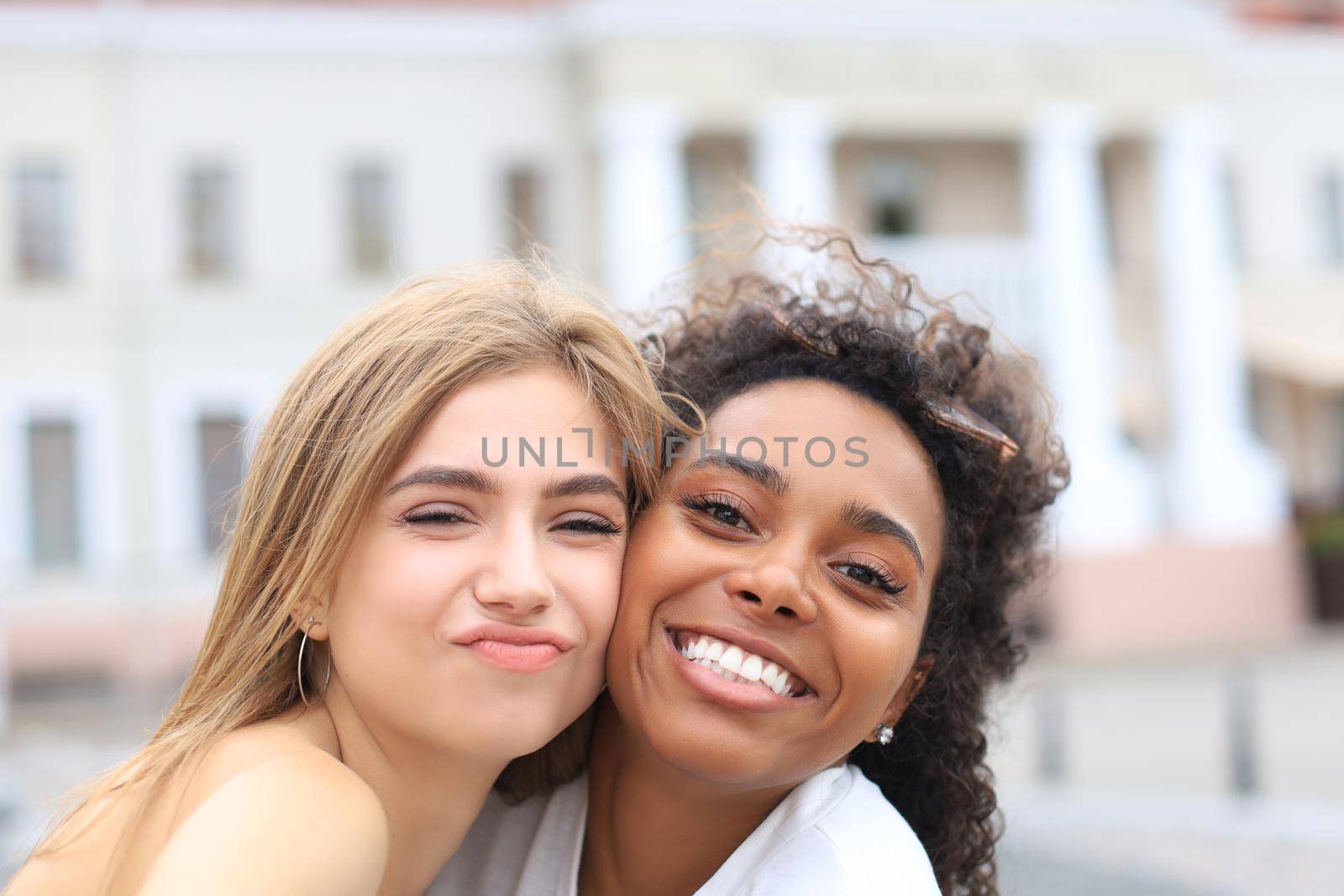 Young smiling hipster women in summer clothes posing on street.Female showing positive face emotions