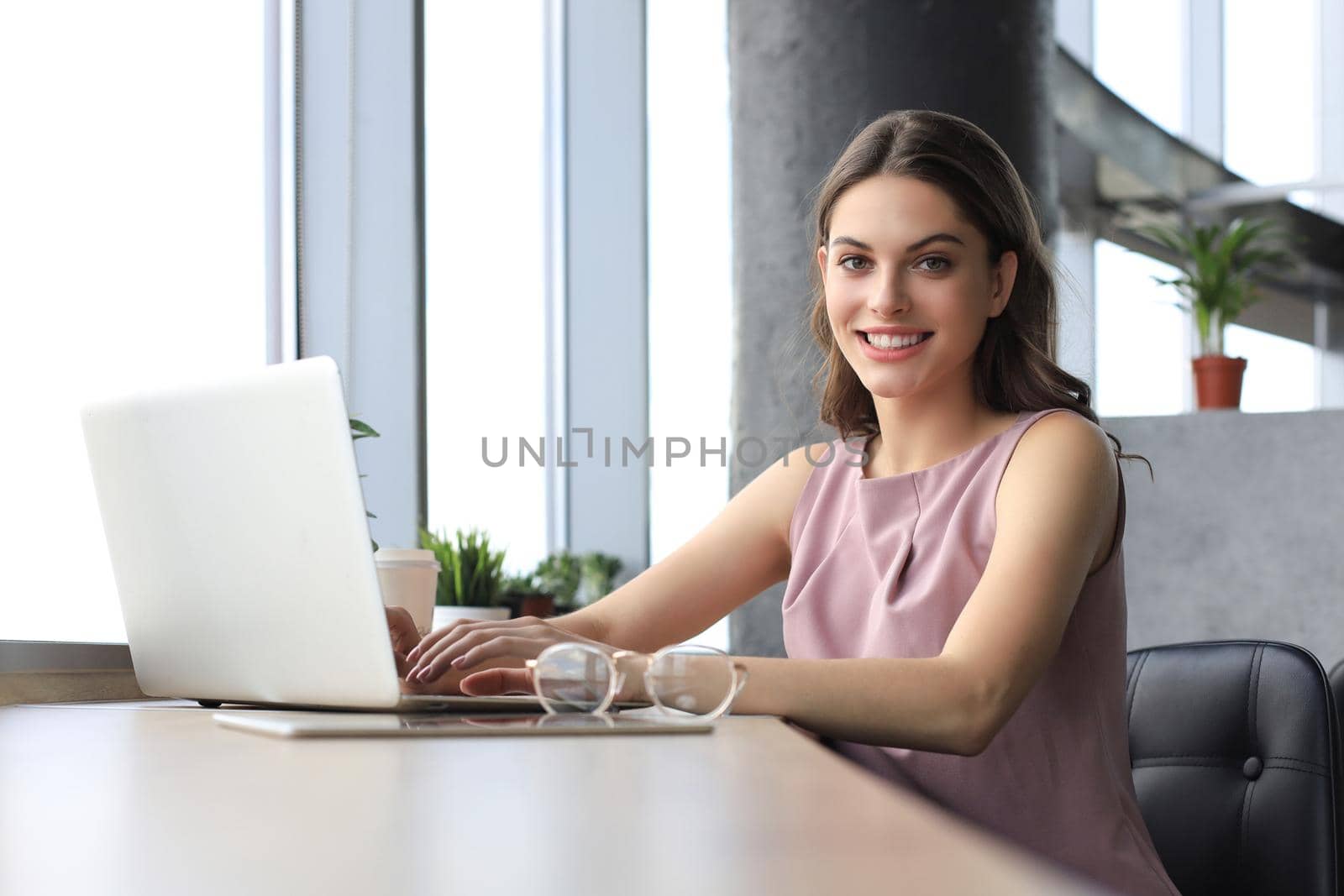 Beautiful smiling business woman is sitting in the office and looking at camera by tsyhun