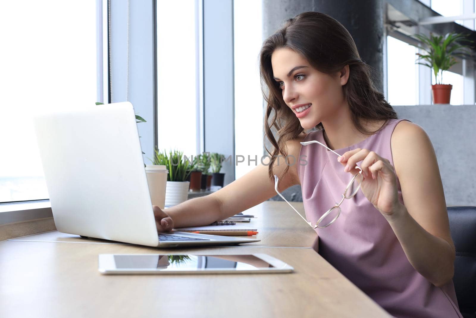 Beautiful business woman in smart casual wear working on laptop in the office.