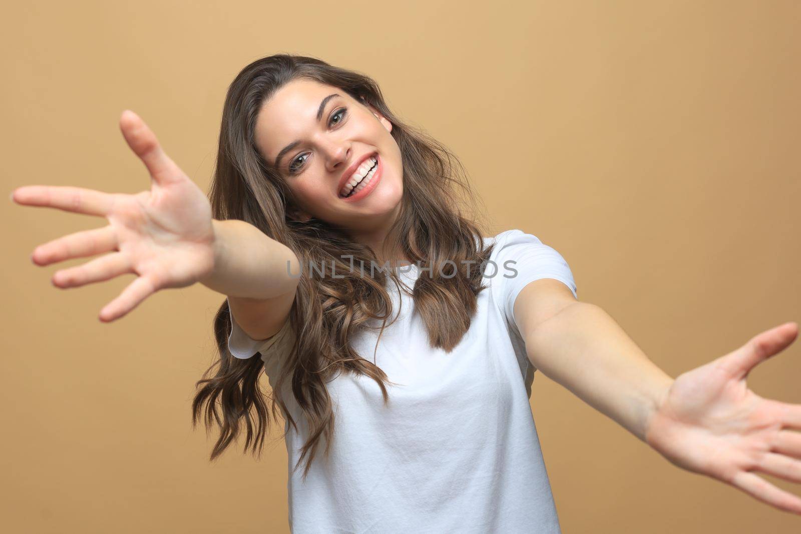 Attractive young brunette woman showing sign follow me on beige background. by tsyhun