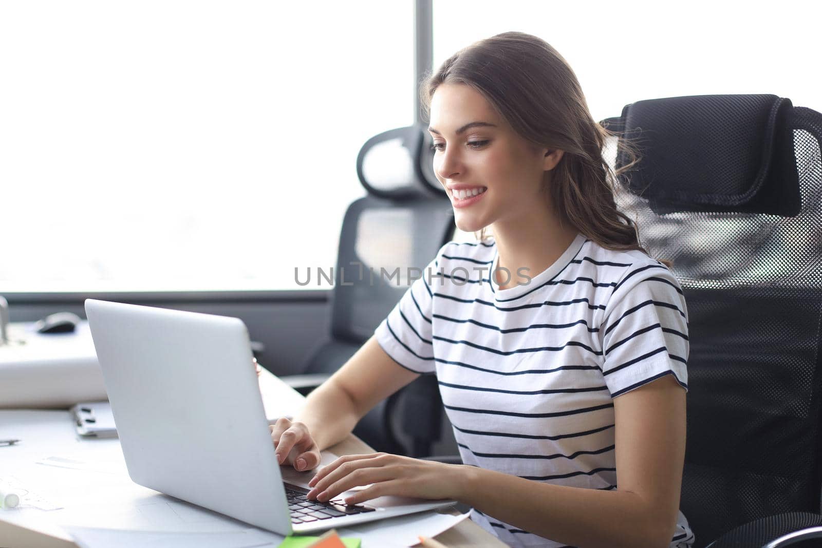 Beautiful business woman in smart casual wear working on laptop in the office.