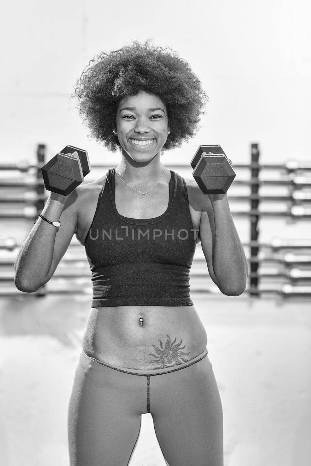 young beautiful African American woman doing bicep curls in a gym