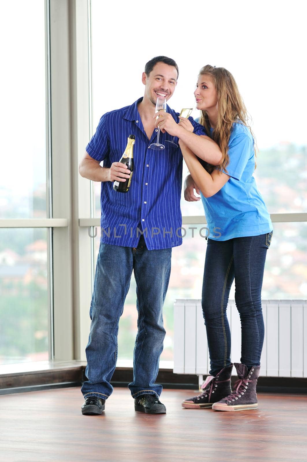 happy couple at big bright comfort apartment celebrate with glasses of champagne