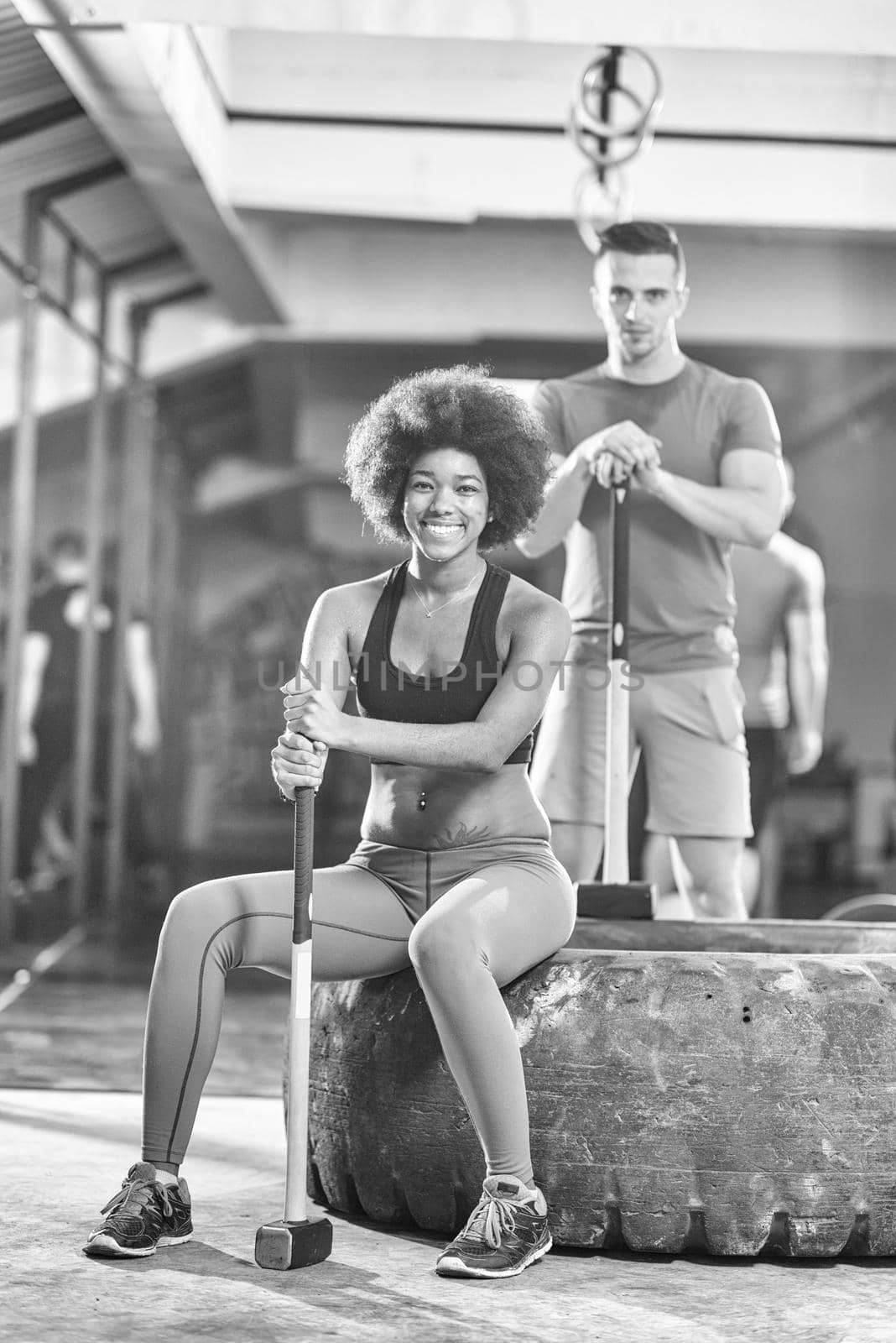 portrait of a young multiethnic couple after training with a sledgehammer and tractor tire