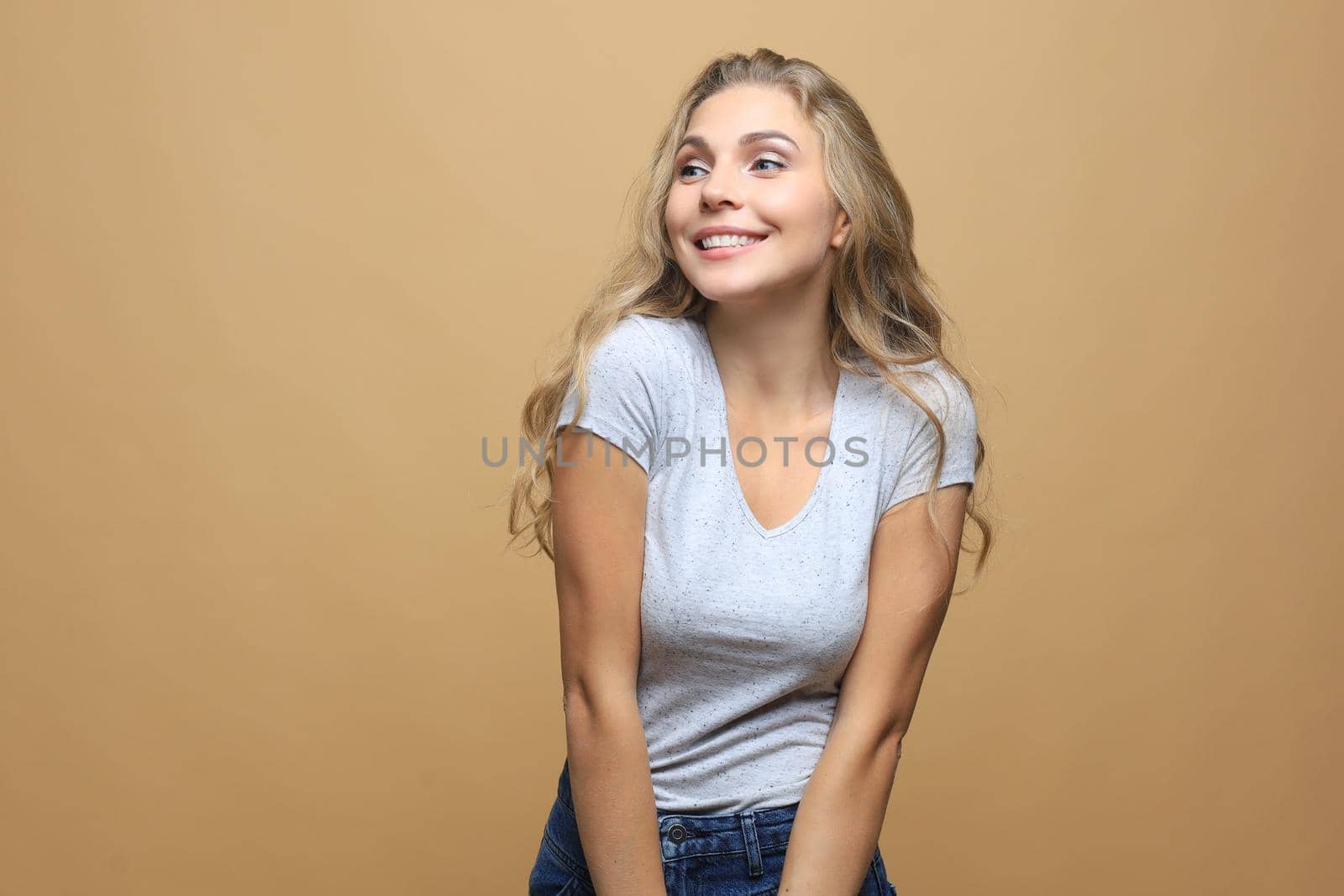 Portrait of young beautiful cheerful girl smiling looking at camera over beige background
