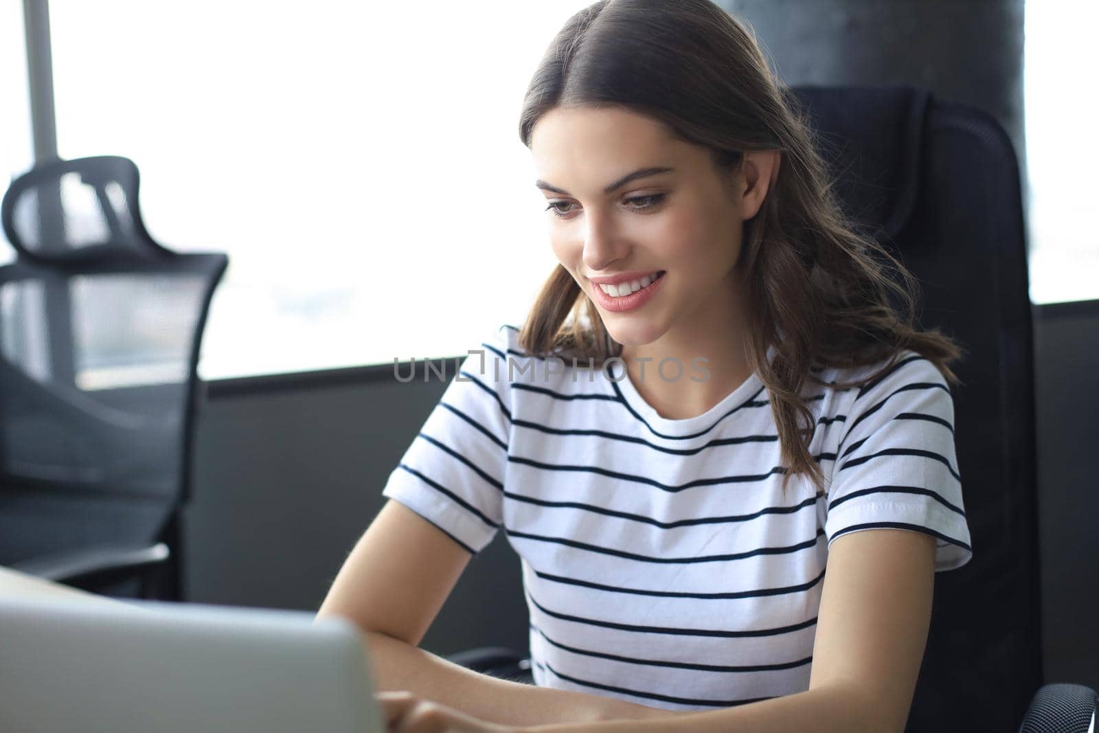 Beautiful business woman in smart casual wear working on laptop in the office.