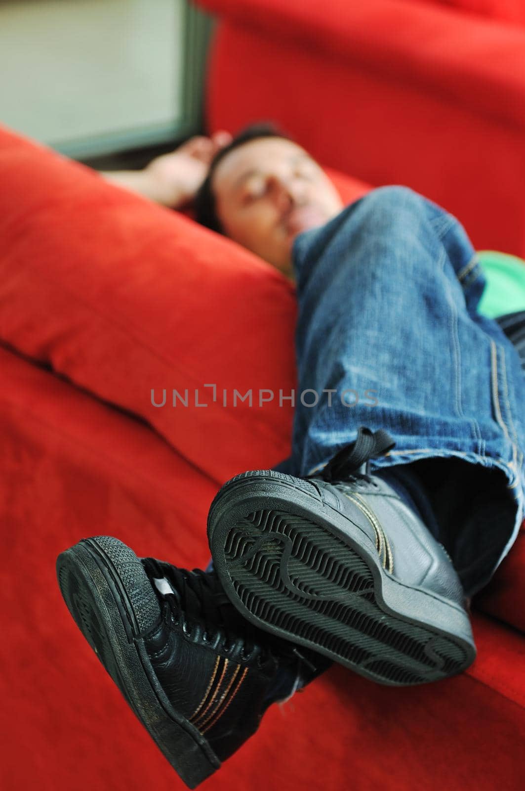 young man relax on red sofa and work on laptop at home indoor 