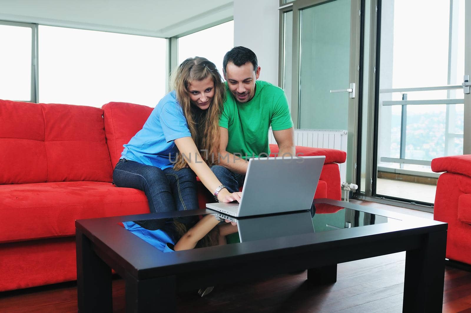 happy young couple have fun and relax at comfort bright apartment and work on laptop computerhappy young couple have fun and relax at comfort bright appartment and work on laptop computer