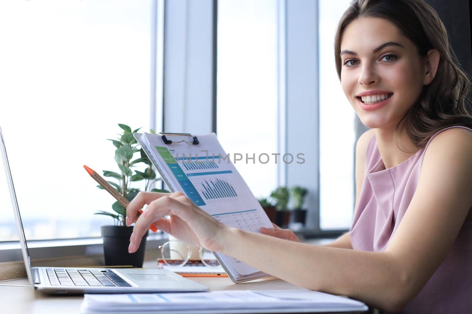 Beautiful young woman writing something down while sitting in modern office