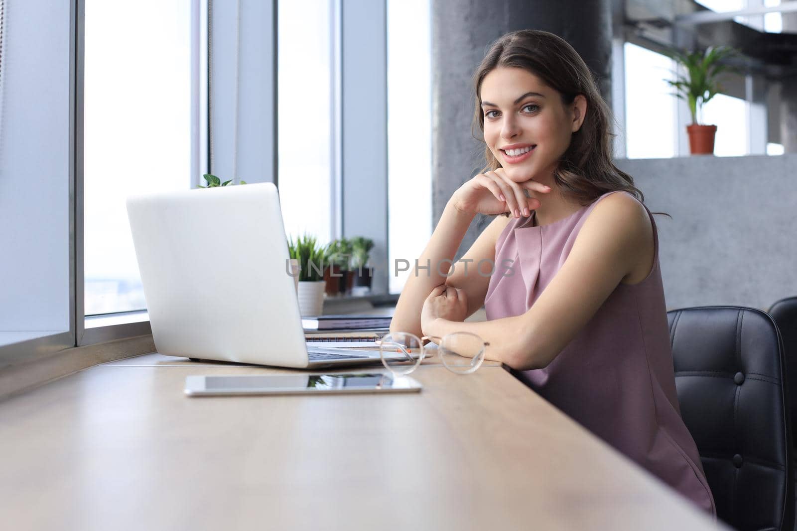 Beautiful smiling business woman is sitting in the office and looking at camera by tsyhun