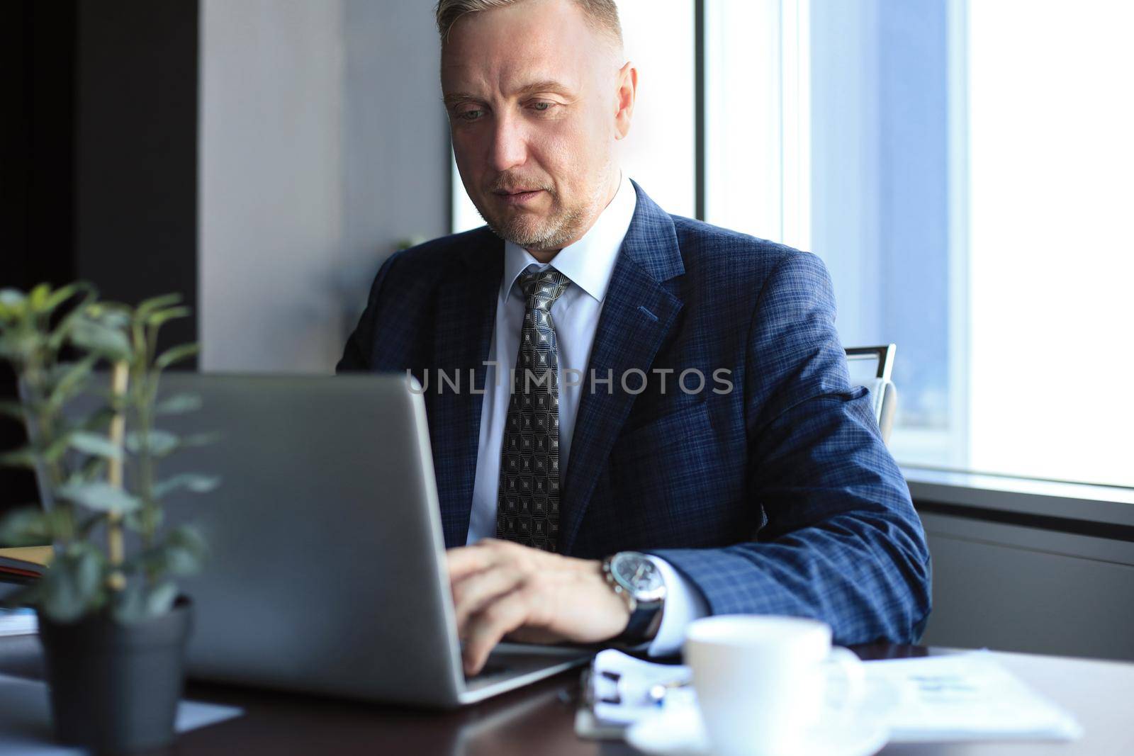 Focused mature businessman deep in thought while sitting at a table in modern office