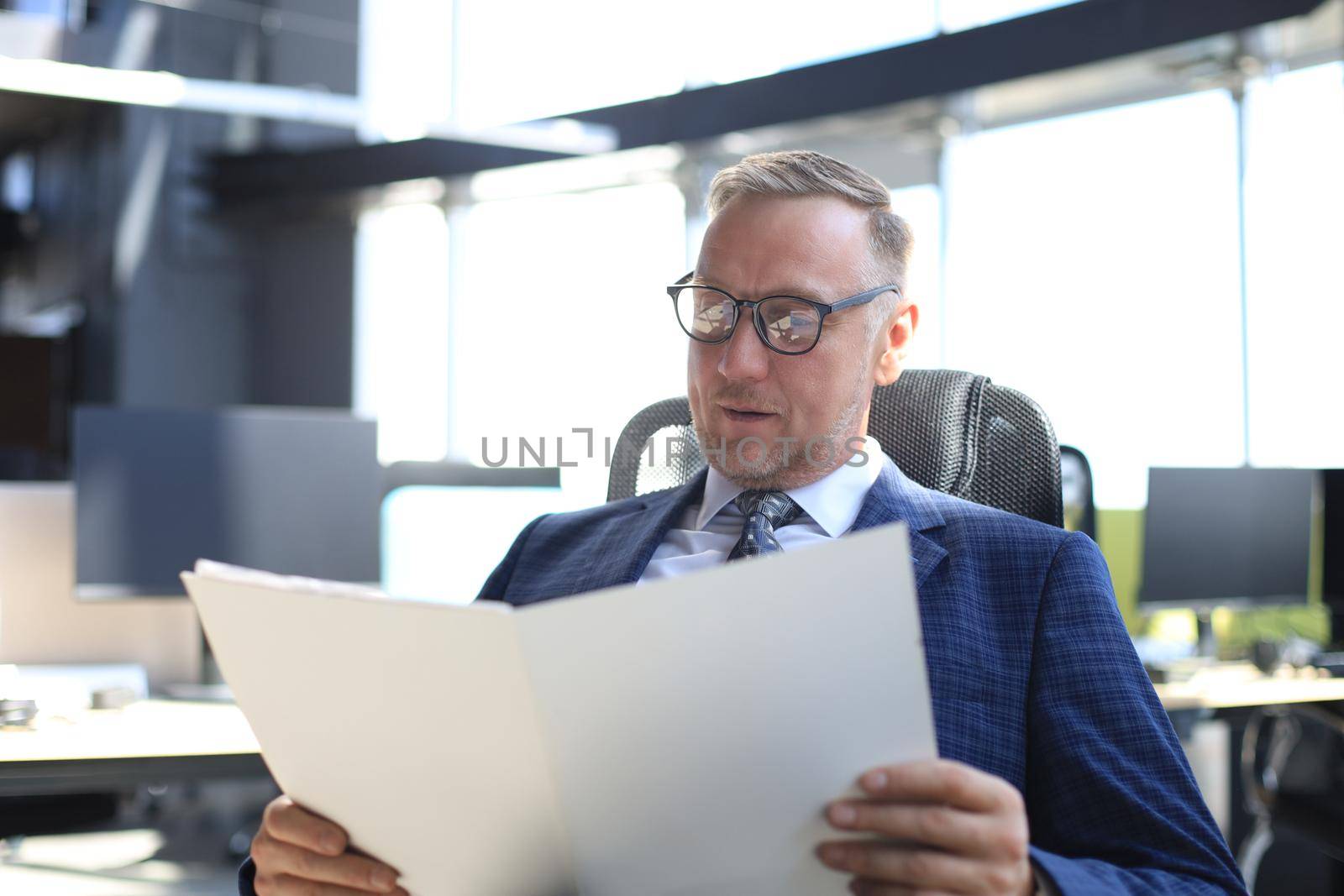 Successful mature entrepreneur is studying documents with attentive and concentrated look