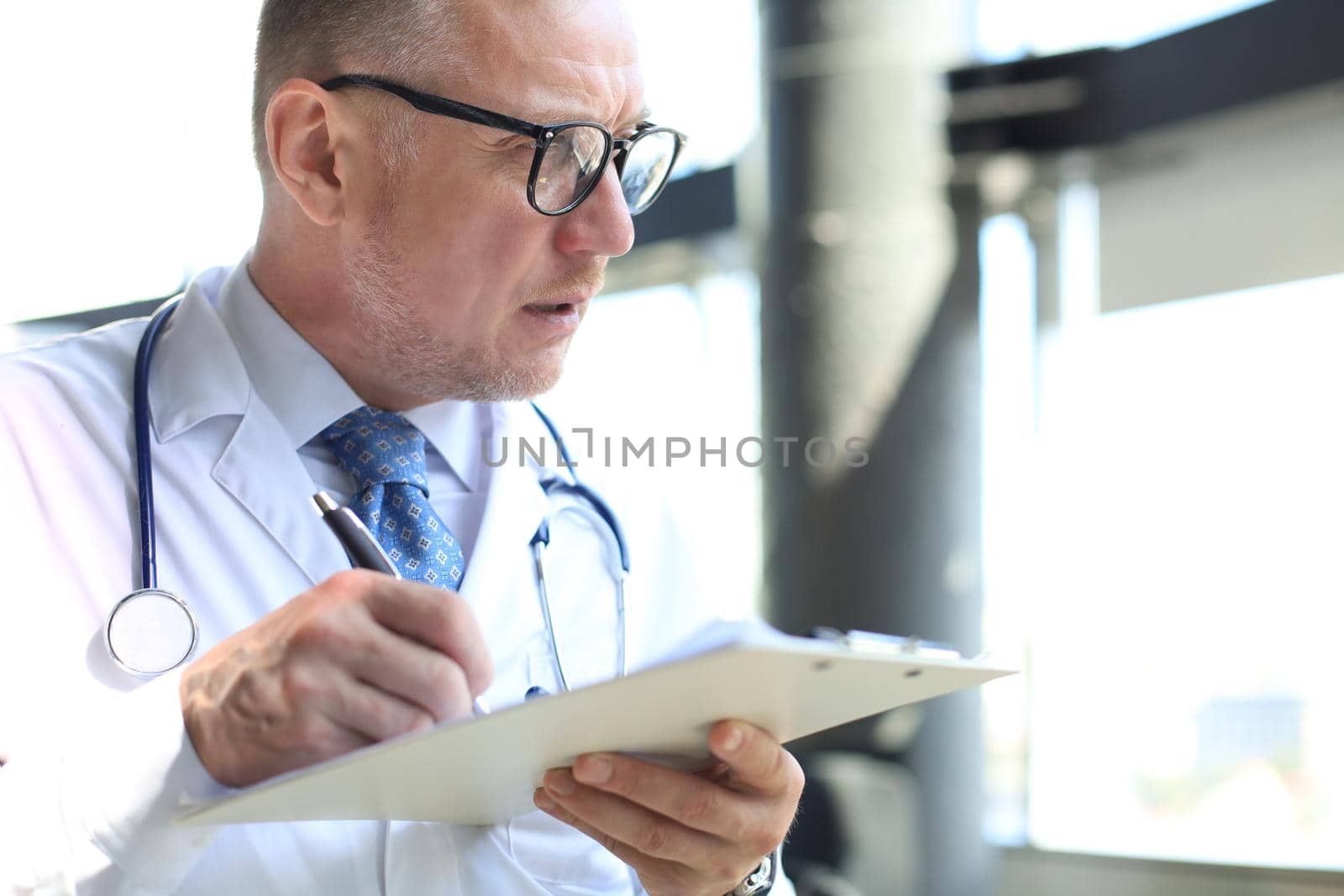 Portrait of focused senior doctor writing reports