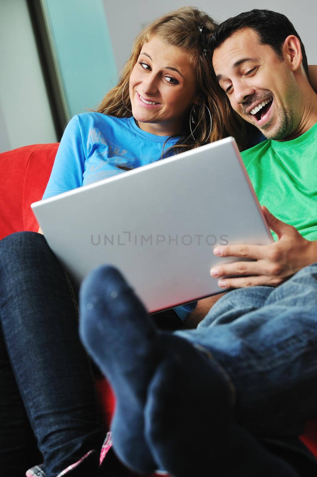 happy young couple have fun and relax at comfort bright apartment and work on laptop computerhappy young couple have fun and relax at comfort bright appartment and work on laptop computer