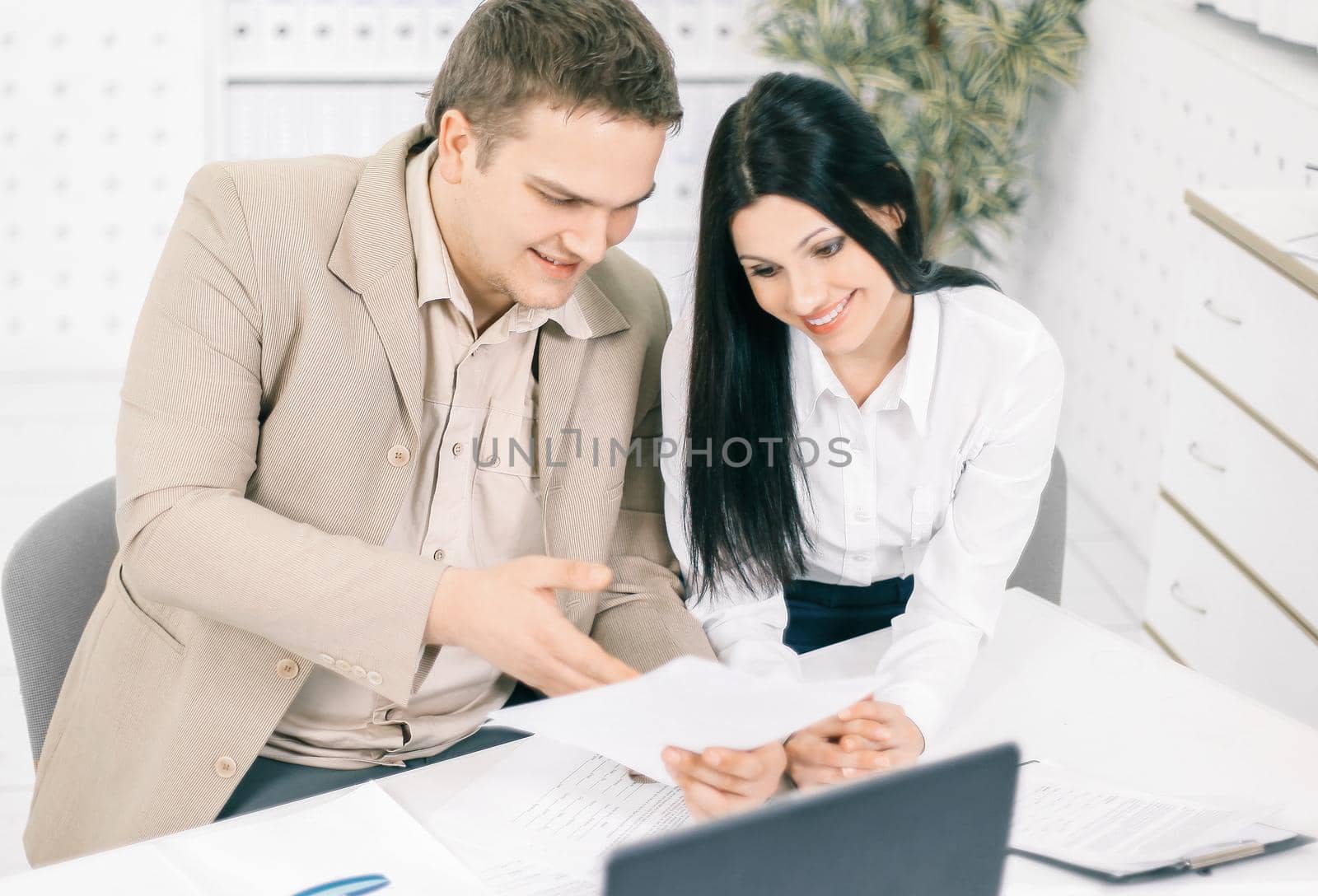 two members of the company discussing marketing schemes,sitting at their Desk