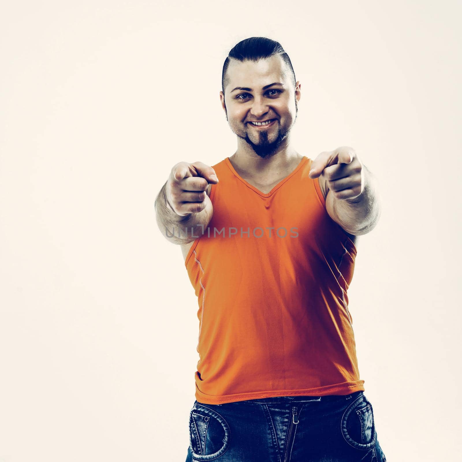 sporty guy - bodybuilder in jeans and orange t-shirt with hand showing forward . the photo has a empty space for your text