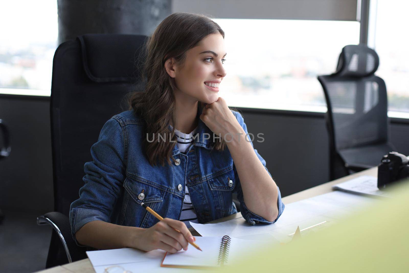 Happy young woman writing something down while working in the office
