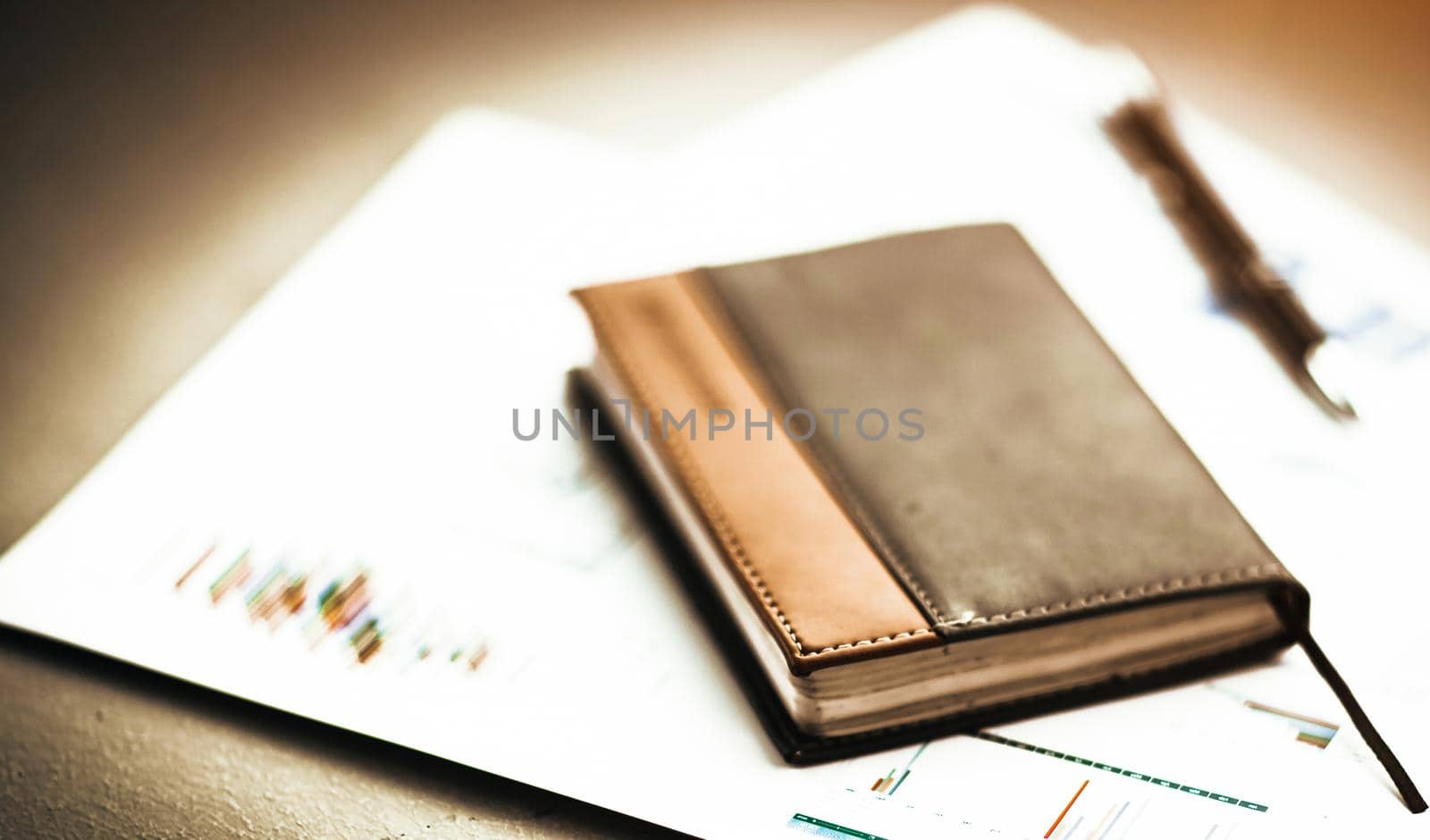 personal organizer and pen on the desk on the background of graphs and charts to your phone