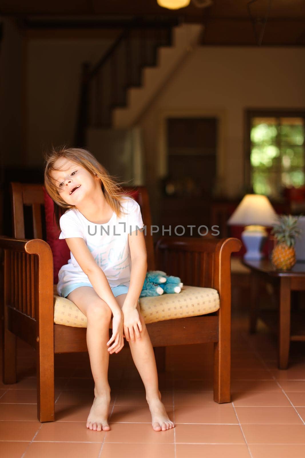 Little happy girl sitting with toy in wooden chair. by sisterspro