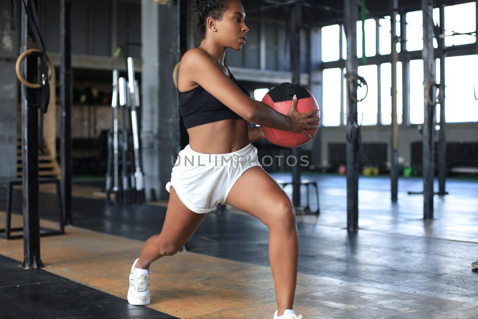 Fit and muscular woman exercising with medicine ball at gym