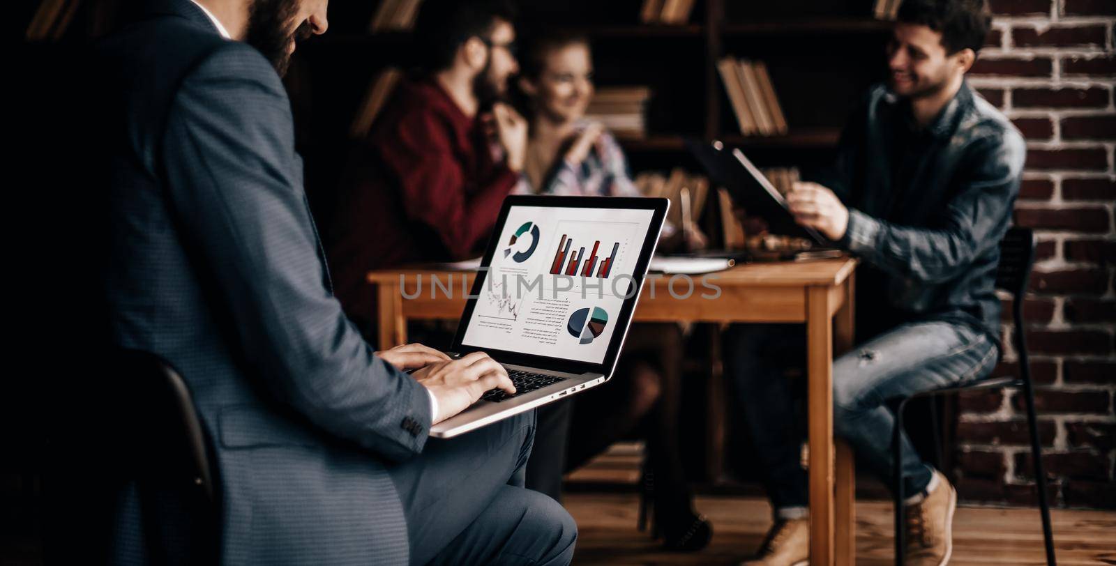 Manager Finance works with the marketing graphics on the laptop on the background of business team workplace in the office